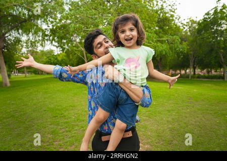 Heureux insouciant jeune père indien et fille enfant jouant à Summer Park.Family et concept de paternité. Banque D'Images