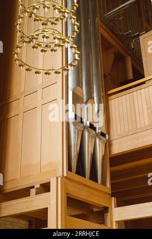 Un gros plan de l'orgue ouest principal (les tuyaux métalliques et la construction en bois) dans l'église de Grundtvig avec un lustre suspendu devant lui Banque D'Images