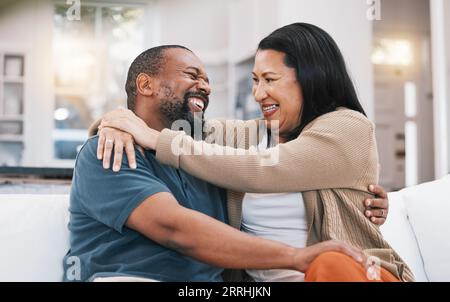 Heureux, câlin et couple mature sur le canapé dans le salon pour le lien, la relation saine et le mariage. Amour, maison et heureux homme et femme noirs embrassent Banque D'Images