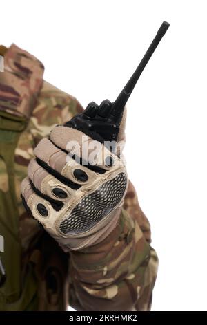 Homme méconnaissable en uniforme de camouflage tenant un talkie-walkie militaire à l'intérieur. Vue rapprochée des postes de radio portables, tenus par un soldat militaire, isolé sur fond de studio blanc. Concept de connexion. Banque D'Images