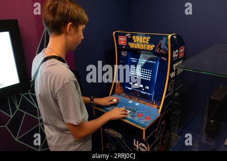 Machine de jeu Taito envahisseurs de l'espace. Simple Space Arcade dans le vieux jeu vidéo rétro 8 bits. Garçon joue à la machine à sous classique. Varsovie, Pologne - 28 juillet 2023. Banque D'Images