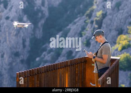 Un jeune homme volant par drone dans les montagnes. Photographie aérienne. Contrôle des drones. Point d'observation près de la cascade de Gubavica en Croatie. Banque D'Images