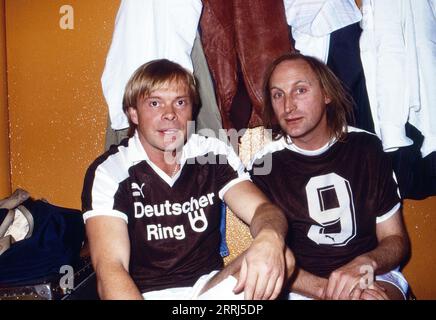 Sänger und Schauspieler Volker Lechtenbrink mit Komiker Otto Waalkes, im Fußball-Trikot Nr. 9, das bekannte Uwe Seeler Trikot beim Hamburger SV, in der Umkleidekabine vor dem Promi-Fußball-Turnier zugunsten der Marathon-Opfer im Stadion am Millerntor in Hamburg, Deutschland, 1987. Banque D'Images