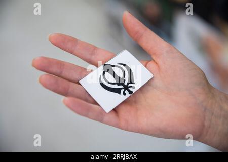 Berlin, Allemagne. 27 août 2023. Une femme tient la carte d’un jeu de mémoire avec le khanda, symbole religieux du sikhisme, au 6e Festival des religions de Berlin. (Scène posée) crédit : Christoph Soeder/dpa/Alamy Live News Banque D'Images