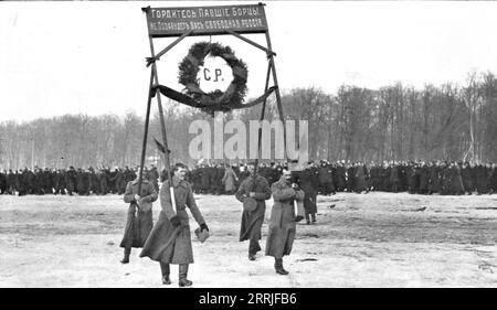 « Les funerailles des morts de la Revolution ; un hommage de l'armée révolutionnaire : soldats portant une couronne surmontée de cette inscription en lettres d'or, sur fond rouge : &lt;&lt;soyez fiers, lutteurs tomb&#xe9;s, la Russie libre ne vous oublie pas. &gt;&gt;', 1917. La Révolution russe : funérailles des morts. Hommage de l'armée révolutionnaire, des soldats portant une couronne avec inscription en or sur fond rouge: "Soyez fiers, combattants tombés, la Russie libre ne vous oubliera pas". Extrait de "l'Album de la Guerre 1914-1919, Volume 2" [l'Illustration, Paris, 1924]. Banque D'Images