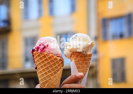 Deux mains tenant un gelato artisanal dans un cône et une vue sur les maisons colorées traditionnelles dans la vieille ville Vieille ville de Nice, Sud de la France Banque D'Images