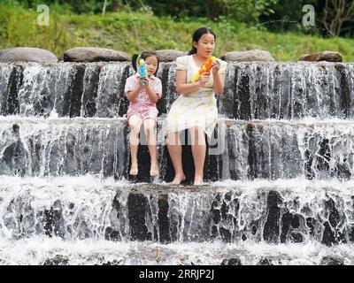 220731 -- JING AN, 31 juillet 2022 -- des enfants jouent avec des pistolets à eau dans le village de Sanping, dans la ville de Zhongyuan, dans le comté de Jing an, province du Jiangxi, dans l'est de la Chine, le 27 juillet 2022. Situé à une altitude de plus de 600 mètres, Zhongyuan Town dans la province de Jiangxi de l'est de la Chine a un taux de couverture forestière de près de 90%. En conséquence, la température moyenne ici est de 6 à 10 degrés Celsius plus froide que celle de la ville voisine de Nanchang, la capitale de la province du Jiangxi, ce qui fait de la ville une station estivale favorable pour les touristes pour échapper à la chaleur estivale. Cet endroit était frappé par la pauvreté, et nous avons gagné notre vie en coupant d Banque D'Images