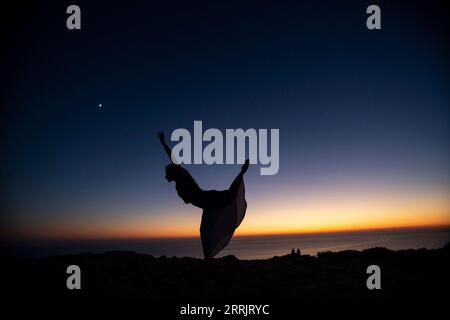 220808 -- GAVDOS, 8 août 2022 -- la photo prise le 3 2022 août montre un danseur qui se produit au coucher du soleil sur l'île de Gavdos en Grèce. GRÈCE-GAVDOS-LIGHTHOUSE MariosxLolos PUBLICATIONxNOTxINxCHN Banque D'Images