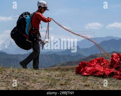 220808 -- XINJIANG, 8 août 2022 -- Chen Ruifeng pratique le parapente dans la banlieue sud d Urumqi, dans la région autonome ouïgoure du Xinjiang du nord-ouest de la Chine, le 24 mai 2022. Né au Xinjiang, Chen Ruifeng, 52 ans, est un amateur de parapente. Il dit qu'il a envie d'avoir ses propres ailes quand le parapente s'ouvre. En 2016, Chen Ruifeng commence à pratiquer le parapente. Plus tard, il a rejoint un club local et a reçu son certificat de pilotage après la formation. Passionné de plein air, il s’engage également dans le Trail running, l’alpinisme et l’escalade sur glace. Selon lui, le terrain unique du Xinjiang, tel Banque D'Images
