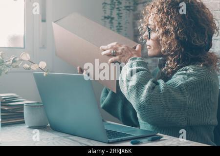 Petit démarrage à la maison concept d'affaires. Une femme préparant le paquet à envoyer après la vente des produits en ligne. Entrepreneur moderne utilisant un ordinateur portable pour vendre et expédier des produits aux clients. Femme d'affaires Banque D'Images