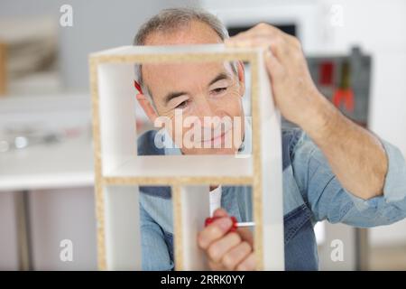 un homme senior qui assemble des meubles Banque D'Images