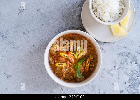 Poulet au curry rouge avec légumes, riz blanc dans un bol sur fond gris vu de dessus Banque D'Images