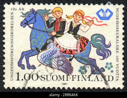 Un timbre imprimé en FINLANDE montre la scène Folk. Garçon et fille en costumes nationaux sur cheval ailé, vers 1981 Banque D'Images