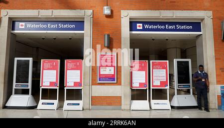 220821 -- LONDRES, le 21 août 2022 -- Un membre du personnel se tient à côté d'avis de grève à l'entrée de Waterloo East Station, à Londres, en Grande-Bretagne, le 20 août 2022. Cet été, alors que de nombreux Britanniques ont opté pour une escapade et que les hubs de transport à travers le Royaume-Uni étaient déjà sous pression, une autre série de grèves a plongé les transports publics dans le chaos cette semaine. Plus de 50 000 travailleurs des réseaux ferroviaires, de métro et de bus ont fait grève pour des raisons de salaire et de conditions de travail de jeudi jusque dans le week-end. Il est conseillé aux passagers de voyager uniquement en train si nécessaire. POUR ALLER AVEC la fonction : TRA Banque D'Images