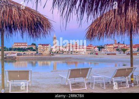 Europe, Croatie, comté de Primorje-Gorski Kotar, île de Rab, chaises longues et parasols sur la plage de sable surplombant la vieille ville de rab en arrière-plan Banque D'Images