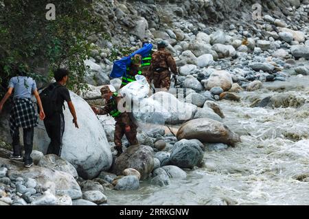 Chine, Erdbeben in Sichuan, Bergungsarbeiten 220908 -- Moxi, 8 septembre 2022 -- les sauveteurs livrent des fournitures par un chemin ascendant le long de la rivière Moxi près de la ville de Moxi, dans le comté de Luding, dans le sud-ouest de la Chine, province du Sichuan, 8 septembre 2022. Certains villageois vivant dans les montagnes près de la ville de Moxi n'ont pas réussi à évacuer en raison des routes endommagées et ont dû installer des tentes temporaires dans des zones relativement sûres après un tremblement de terre de magnitude 6,8 qui a secoué le comté de Luding dans la province du Sichuan. Les secours, y compris de l'eau potable et des tentes, ont été acheminés par des sauveteurs et des bénévoles via des ponts temporaires et des routes de montagne. Banque D'Images