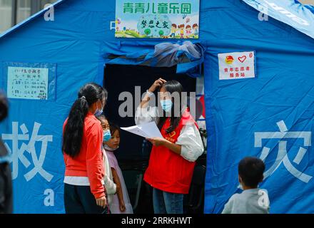 220910 -- LUDING, 10 septembre 2022 -- Luo Lian 2nd R enregistre les enfants avant qu'ils n'entrent dans la salle de classe sous tente à l'abri de secours contre les tremblements de terre de l'école secondaire Luding n° 2 dans le comté de Luding, dans la province du Sichuan du sud-ouest de la Chine, le 10 septembre 2022. Luo Lian, 32 ans, est enseignante de maternelle dans la ville de Lengqi, dans le comté de Luding. Après un tremblement de terre de magnitude 6,8 qui a secoué le comté de Luding, elle s'est portée volontaire pour travailler au refuge de secours contre les tremblements de terre de l'école secondaire n° 2 de Luding, où plus de 800 villageois, dont environ 50 enfants de la ville de Detuo, l'une des zones les plus durement touchées, ont été temporairement relogés. Avec Othe Banque D'Images