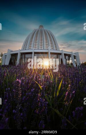 Temple BA 'í à Hofheim im Taunus. Belle église ou lieu de culte au lever du soleil. Un bâtiment moderne en dôme dans un paysage avec de la lavande au premier plan. Allemagne Banque D'Images