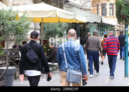 Helsinki, Finlande - 5 septembre 2023 : les gens se promènent sur le trottoir de la rue Pohjoisesplanadi à côté des cafés et des restaurants avec des places assises à l'extérieur. Banque D'Images