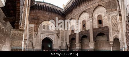 Façade à la décoration riche dans la cour de l'Attarine Medersa à Fès, au Maroc Banque D'Images