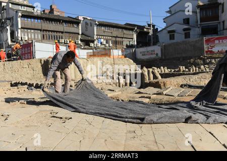 221011 -- WENZHOU, 11 octobre 2022 -- Un membre du personnel couvre la fondation d'un bâtiment ancien sur le site archéologique de l'ancien port de Shuomen à Wenzhou, dans la province du Zhejiang de l'est de la Chine, le 10 octobre 2022. Le site archéologique de l'ancien port de Shuomen a été découvert à la fin de 2021, avec des ruines de bâtiments anciens, des épaves et des pièces de porcelaine mises au jour dans les fouilles archéologiques suivantes. Selon l'Administration nationale du patrimoine culturel, la découverte est importante pour les études de l'ancienne route maritime de la soie. CHINE-ZHEJIANG-WENZHOU-SHUOMEN ANCIEN PORT-RUINES CN WEN Banque D'Images