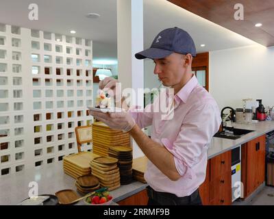 221026 -- HAIKOU, 26 octobre 2022 -- Sebastian Hahn, de Berlin, Allemagne, décore un morceau de gâteau dans son café de Haikou, dans la province de Hainan du sud de la Chine, le 18 octobre 2022. Mélangeant sirop de bière, lait et expresso, Sebastian Hahn a habilement fait une tasse de latte de bière qui est une boisson de spécialité de son café. Cela a un goût très spécial et personnellement je l'aime beaucoup, a-t-il dit. POUR ALLER AVEC à travers la Chine : l'homme allemand poursuit une nouvelle carrière et l'amour à Hainan CHINE-HAINAN-ALLEMAND HOMME-NOUVELLE CARRIÈRE ZhouxHuimin PUBLICATIONxNOTxINxCHN Banque D'Images