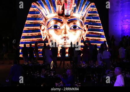 221104 -- LOUXOR ÉGYPTE, 4 novembre 2022 -- des gens se tiennent devant un tableau géant montrant le masque doré du roi Toutankhamon lors d'une célébration marquant le centenaire de la découverte de la tombe du roi Toutankhamon au temple de Louxor à Louxor, en Égypte, le 4 novembre 2022. L'Egypte a organisé vendredi des événements pour célébrer le centenaire de la découverte de la tombe du roi Toutankhamon en 1922. Toutankhamon, qui est monté sur le trône à l'âge de neuf ans et est mort à 19 ans, est le pharaon le plus connu au monde de l'Egypte ancienne. Le jeune roi régna de 1332 av. J.-C. à 1323 av. J.-C., au cours d'une période connue sous le nom de nouvel Empire dans l'ancien Egyp Banque D'Images