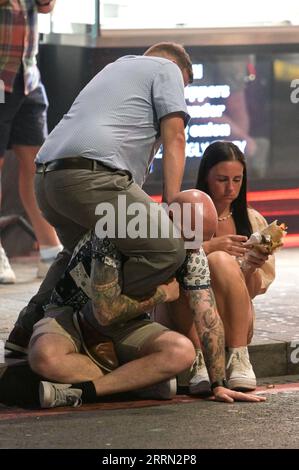 Broad Street, Birmingham, 8 septembre 2023 - Revellers a pris à Broad Street à Birmingham vendredi soir où ils ont apprécié des températures de 27 degrés. Cela signifiait qu'ils pouvaient profiter de porter des vêtements skimpy comme ils faisaient leur chemin de bar en bar. Deux hommes ont été repérés jouant au combat sur le trottoir alors que leur ami essayait de profiter d'un plat à emporter après une journée de boisson. Crédit : Arrêter Press Media/Alamy Live News Banque D'Images