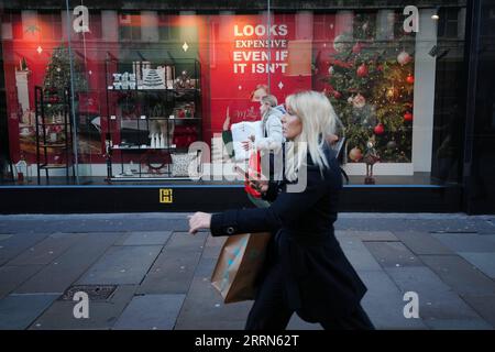 221214 -- MANCHESTER, 14 déc. 2022 -- des gens passent devant un panneau promotionnel à Manchester, Grande-Bretagne, 13 déc. 2022. La flambée de l’inflation a forcé de nombreux ménages à réévaluer leurs dépenses pour Noël cette année. Photo de /Xinhua BRITAIN-MANCHESTER-CHRISTMAS-INFLATION JonxSuper PUBLICATIONxNOTxINxCHN Banque D'Images