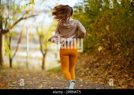 Bonjour automne. Vu de derrière femme dans des vêtements de fitness dans le parc en cours d'exécution. Banque D'Images