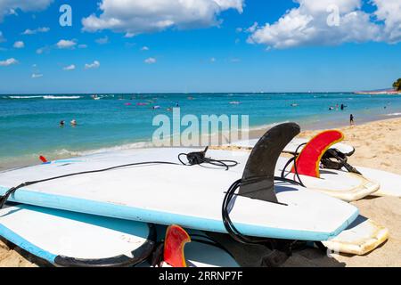 Planches de surf montrant des palmes et des sangles de cheville de laisse couchées sur le sable à Waikiki Beach à Honolulu Hawaii. Arrière-plan flou. Banque D'Images