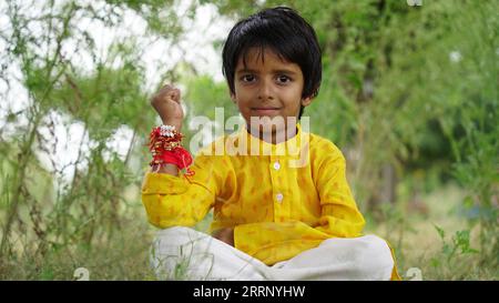 Frère et sœur hindous en vêtements ethniques tenant des bonbons indiens et boîte cadeau à l'occasion du festival Raksha Bandhan Banque D'Images