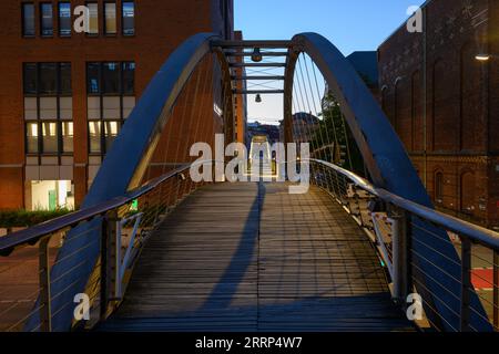Hambourg, Allemagne - juillet 13 2023 : passerelle Kehrwiedersteg ou pont Kehrwieder dans l'heure bleue au crépuscule illuminé. Banque D'Images