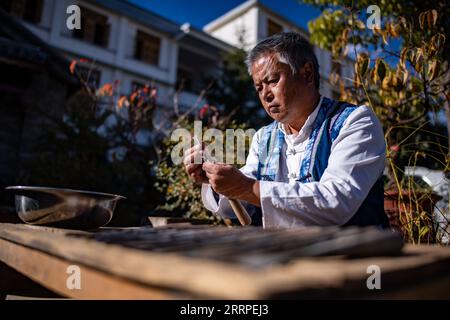 230317 -- JIANCHUAN, 17 mars 2023 -- Duan Sixing polit des outils pour la sculpture sur bois dans le comté de Jianchuan, préfecture autonome de Dali Bai, province du Yunnan dans le sud-ouest de la Chine, 1 décembre 2022. Le comté de Jianchuan, situé dans la préfecture autonome de Dali Bai dans la province du Yunnan, au sud-ouest de la Chine, a une longue histoire dans la sculpture sur bois datant des dynasties Tang 618-907 et Song 960-1279. Les compétences en sculpture se sont progressivement développées, passant d'un relief à une couche à un relief creux à sept couches, et sont maintenant appliquées à la fabrication de pièces d'architecture, de meubles en bois, de peintures murales et de souvenirs touristiques. Un standard élevé Banque D'Images