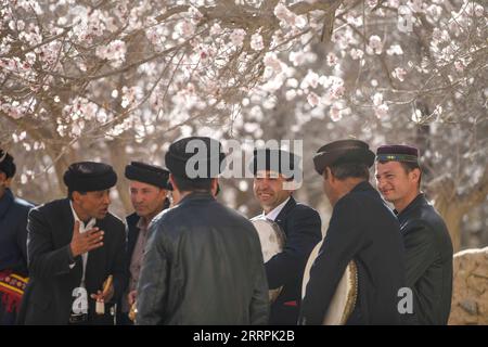 230329 -- Akto, le 29 mars 2023 -- des villageois bavardent au milieu des abricotiers dans le village de Bahrigzi, dans le canton de Tar Tajik, comté d'Akto, région autonome ouïgour du Xinjiang, au nord-ouest de la Chine, le 28 mars 2023. Tar Tajik Township, niché dans l'arrière-pays des montagnes Kunlun, est un village touristique rural national clé dans le comté d'Akto, dans le nord-ouest de la Chine de la région autonome ouïgour du Xinjiang. Comme le temps se réchauffe, les fleurs d'abricot sont en pleine floraison ici. Le magnifique paysage naturel et les coutumes folkloriques uniques attirent de nombreux touristes. Ces dernières années, le gouvernement local a accéléré la construction d'infra Banque D'Images