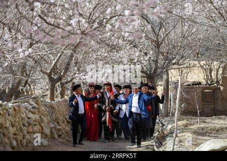 230329 -- Akto, le 29 mars 2023 -- des gens locaux se produisent lors d'une cérémonie de mariage traditionnelle pour les touristes dans le village de Bahrigzi, dans le canton de Tar Tajik, dans le comté d'Akto, dans la région autonome ouïgoure du Xinjiang, au nord-ouest de la Chine, le 28 mars 2023. Tar Tajik Township, niché dans l'arrière-pays des montagnes Kunlun, est un village touristique rural national clé dans le comté d'Akto, dans le nord-ouest de la Chine de la région autonome ouïgour du Xinjiang. Comme le temps se réchauffe, les fleurs d'abricot sont en pleine floraison ici. Le magnifique paysage naturel et les coutumes folkloriques uniques attirent de nombreux touristes. Ces dernières années, le gouvernement local a acc Banque D'Images