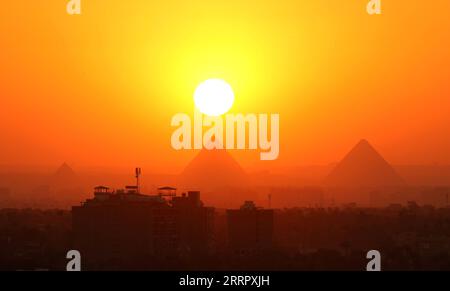 230416 -- LE CAIRE, le 16 avril 2023 -- cette photo prise le 15 avril 2023 montre les pyramides de Gizeh au coucher du soleil vues du Caire, en Égypte. ÉGYPTE-LE CAIRE-PYRAMIDES DE GIZEH-COUCHER DE SOLEIL SuixXiankai PUBLICATIONxNOTxINxCHN Banque D'Images