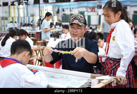 230418 -- GUANGZHOU, le 18 avril 2023 -- Wang Xinyuan guide des élèves dans un cours sur la broderie de Guangzhou dans une école primaire du district de Liwan à Guangzhou, dans la province du Guangdong du sud de la Chine, le 12 octobre 2022. La broderie cantonaise est l'une des quatre broderies célèbres en Chine. La broderie de Guangzhou, qui fait partie de la broderie cantonaise, remonte à la dynastie Tang de 618-907 et a une histoire de plus de 1 000 ans. Bénéficiant de plus de 30 types de points de suture, la broderie de Guangzhou est bien connue pour la composition compliquée, l'image vive, la couleur riche et le lustre, et des styles variés. En mai 2006, il a été répertorié comme Banque D'Images