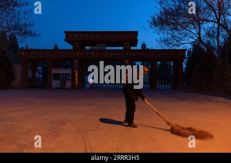 230430 -- YECHENG, le 30 avril 2023 -- Eniwar Emer balaie le sol à l'entrée du cimetière des martyrs de Yecheng avant l'aube à Yecheng, dans la région autonome ouygur du Xinjiang du nord-ouest de la Chine, le 16 avril 2023. Chaque année en avril, des fleurs fleurissent dans le cimetière des martyrs de Yecheng, dans la région autonome ouïgoure du Xinjiang, au nord-ouest de la Chine, où 233 martyrs ont été enterrés. Je prendrai bien soin du cimetière, a déclaré Eniwar Emer, 53 ans, devant la pierre tombale de son père. Eniwar est un gardien de deuxième génération pour le cimetière des martyrs de Yecheng, suivant les traces de son père Emer Yit, qui avait maintenu le gr Banque D'Images