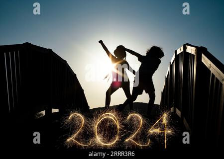 Numéro 2022 étincelants écrits, modèle créatif de superposition pour carte de voeux de vacances ou affiche pour une fête garçons et filles silhouettes dansant o Banque D'Images