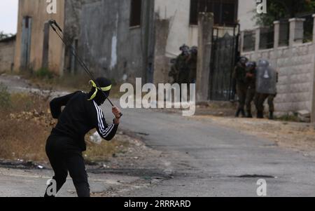 230519 -- KUFR QADOOM, le 19 mai 2023 -- Un manifestant palestinien utilise une fronde pour lancer une pierre sur des soldats israéliens lors d'affrontements à la suite d'une manifestation contre l'expansion des colonies juives dans le village de Kufr Qadoom, en Cisjordanie, près de Naplouse, le 19 mai 2023. Photo de /Xinhua MIDEAST-KUFR QADOOM-CLASHS NidalxEshtayeh PUBLICATIONxNOTxINxCHN Banque D'Images