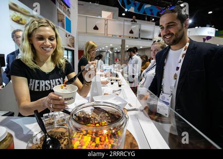 230523 -- CHICAGO, le 23 mai 2023 -- un exposant met des garnitures sur un plat de crème glacée pour un visiteur à l'exposition Sweets and snacks à Chicago, aux États-Unis, le 23 mai 2023. Le salon des sucreries et des collations 2023 se tient au McCormick place à Chicago du 22 au 25 mai. Photo de /Xinhua U.S.-CHICAGO-BONBONS ET COLLATIONS EXPO VincentxD.xJohnson PUBLICATIONxNOTxINxCHN Banque D'Images