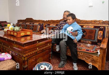 230531 -- NGARI, le 31 mai 2023 -- Un fils et un petit-fils de Losang Zhamdu regardent la télévision dans leur maison de cinquième génération dans le village de Demqog, canton de Zhaxigang, comté de Gar, préfecture de Ngari, région autonome du Tibet du sud-ouest de la Chine, le 28 mai 2023. Assis au soleil devant sa résidence dans le village de Demqog, dans le canton de Zhaxigang, dans le comté de Gar dans la préfecture de Ngari au Tibet, Losang Zhamdu, 84 ans, a raconté une histoire des cinq maisons dans lesquelles il avait vécu. Ma mère et moi vivions ensemble dans une tente faite de poils de yak, tous nos biens étaient une veste de fourrure de chèvre et une couverture tibétaine usée, se souvient Losang Zhamdu, le Banque D'Images