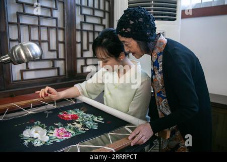 230609 -- CHONGQING, le 9 juin 2023 -- Kang Ning R enseigne à une apprentie à fabriquer des œuvres de broderie Shu dans son atelier du district de Yuzhong, dans la municipalité de Chongqing, au sud-ouest de la Chine, le 14 mai 2023. Kang, qui a près de 70 ans, est l’un des deux héritiers représentatifs de la broderie Shu, un élément du patrimoine culturel immatériel national en Chine. Kang a commencé à apprendre les techniques de fabrication de la broderie Shu quand elle a commencé à travailler à l'âge de 23 ans. Elle a créé sa propre technique qui permet de coudre la broderie de différentes formes et couleurs des deux côtés simultanément, avec le contenu Banque D'Images