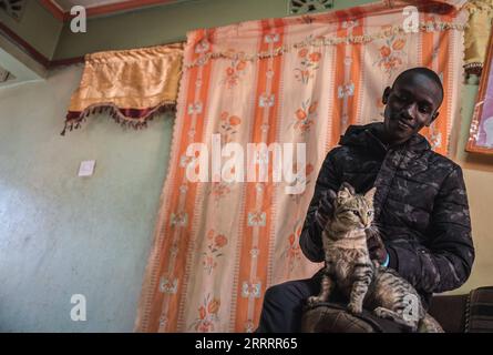 230611 -- ITEN, 11 juin 2023 -- le coureur kenyan Kelvin Kimtai Chepsigor de l'Université Kisii caresse un chat dans un camp d'entraînement à Iten, au Kenya, le 5 juin 2023. Vers 6 heures du matin, la première lumière du matin brille sur l'arche emblématique écrite avec Home of Champions à Iten, les coureurs se sont réunis ici pour se saluer avec une première bosse du poing, étirer leurs muscles et se préparer pour la première séance d'entraînement de la journée. Avec une altitude moyenne de 2 400 mètres, Iten se trouve à l'ouest du Kenya, près de la vallée du Grand Rift en Afrique de l'est. C'est un lieu idéal d'entraînement de course à pied de longue distance et est le berceau de ma Banque D'Images