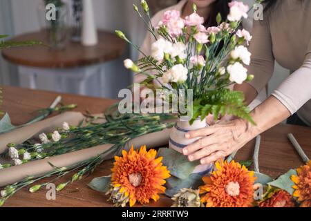 Femme senior et fille adulte créant beau bouquet dans le salon. Concept d'activités familiales et de loisirs Banque D'Images