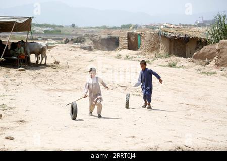 230620 -- ISLAMABAD, le 20 juin 2023 -- des garçons jouent avec des pneus dans un camp de réfugiés lors de la Journée mondiale des réfugiés à Islamabad, au Pakistan, le 20 juin 2023. Le Président pakistanais Arif Alvi a déclaré que son pays continuait d accueillir l une des plus importantes populations de réfugiés au monde, témoignant de la détermination et de l engagement indéfectibles du Pakistan en faveur du bien-être et du rapatriement librement consenti des réfugiés. Dans son message à l'occasion de la Journée mondiale des réfugiés, qui a été célébrée mardi, Alvi a déclaré que, ce jour-là, nous nous souvenons des immenses contributions du gouvernement et du peuple pakistanais dans l'accueil de millions de réfugiés afghans Banque D'Images