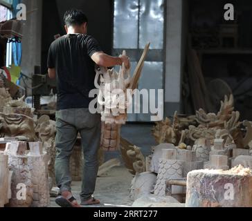 230624 -- FUZHOU, 24 juin 2023 -- Un artisan porte une tête de dragon en bois nouvellement sculptée dans une usine de bateaux-dragons à Minhou, dans la province du Fujian du sud-est de la Chine, le 12 juin 2023. Le festival des bateaux-dragons, également connu sous le nom de festival de Duanwu, tombe traditionnellement le cinquième jour du cinquième mois du calendrier lunaire chinois. La compétition de bateaux-dragons, une partie traditionnelle du festival, a gagné en popularité des deux côtés du détroit de Taiwan, suscitant l'excitation à un large éventail de personnes. Située sur la côte sud-est de la Chine, la province du Fujian est idéale pour les sports nautiques avec son large SCAT Banque D'Images