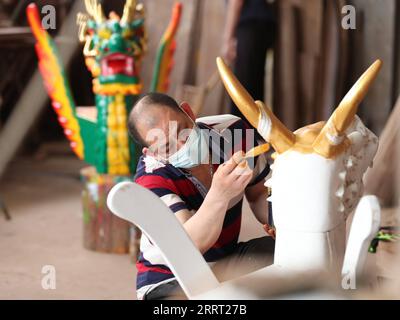 230624 -- FUZHOU, 24 juin 2023 -- Un artisan peint une tête de dragon en bois nouvellement sculptée dans une usine de bateaux-dragons à Minhou, dans la province du Fujian du sud-est de la Chine, le 12 juin 2023. Le festival des bateaux-dragons, également connu sous le nom de festival de Duanwu, tombe traditionnellement le cinquième jour du cinquième mois du calendrier lunaire chinois. La compétition de bateaux-dragons, une partie traditionnelle du festival, a gagné en popularité des deux côtés du détroit de Taiwan, suscitant l'excitation à un large éventail de personnes. Située sur la côte sud-est de la Chine, la province du Fujian est idéale pour les sports nautiques avec son large scatt Banque D'Images