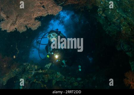 Plongeur avec torche à l'intérieur de l'épave, site de plongée Liberty Wreck, Tulamben, Karangasem, Bali, Indonésie Banque D'Images